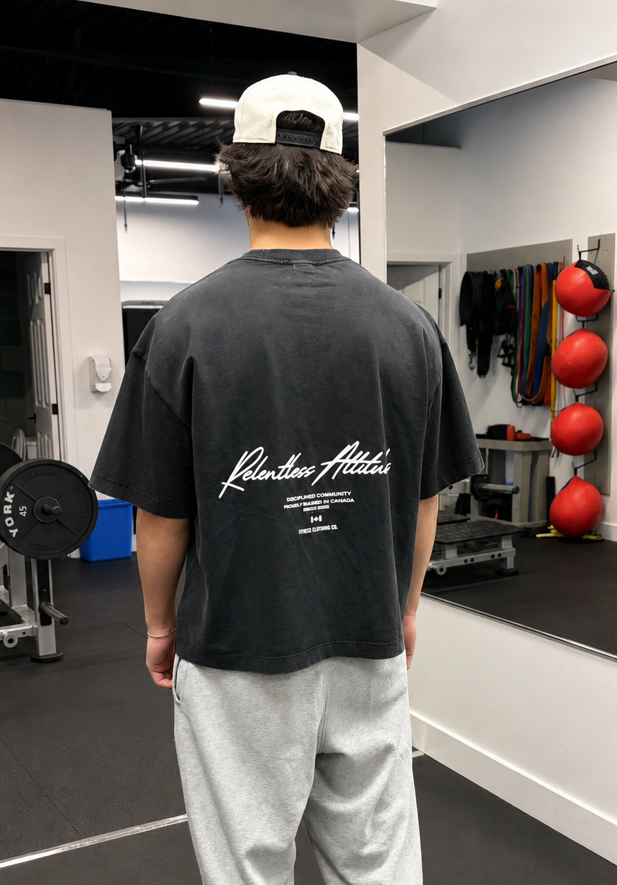 A young muscular man wearing a black washed baggy t-shirt at the gym